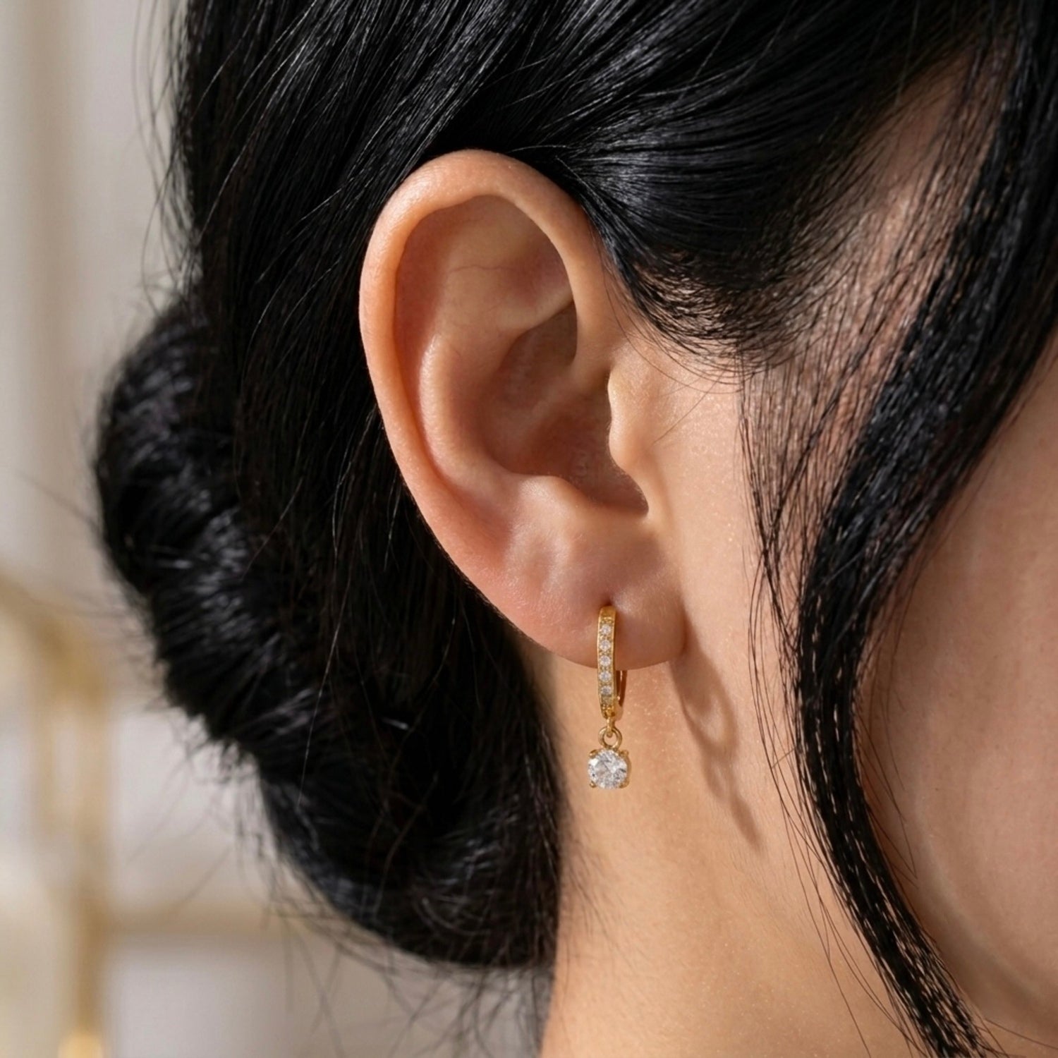 A gold-plated hoop earrings for women featuring a sparkling round-cut crystal drop, shown on a model