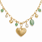A close-view of a gold-plated stainless steel chain for women featuring paperclip links and a variety of charms including a textured gold heart, green beads, and crystal accents.