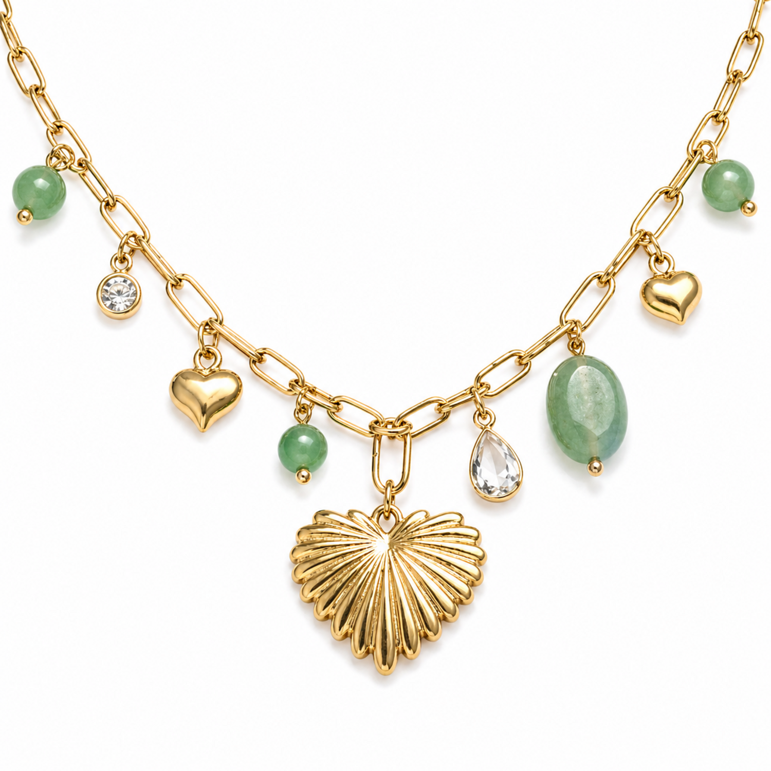 A close-view of a gold-plated stainless steel chain for women featuring paperclip links and a variety of charms including a textured gold heart, green beads, and crystal accents.
