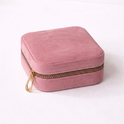 velvet travel size jewellery box organizer in mauve color with golden zipper displayed closed on a flat surface