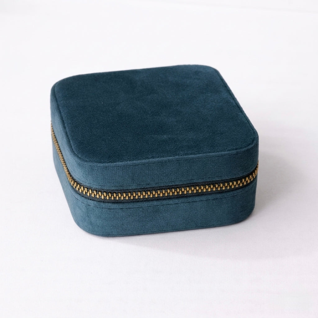 Teal Blue velvet jewelry box with a gold zipper on a white background