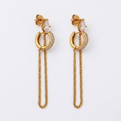 A close-view of a pair of gold-plated ear chain earrings for women connecting a crystal hoop to a marquise-cut crystal stud with a fine gold plated chain