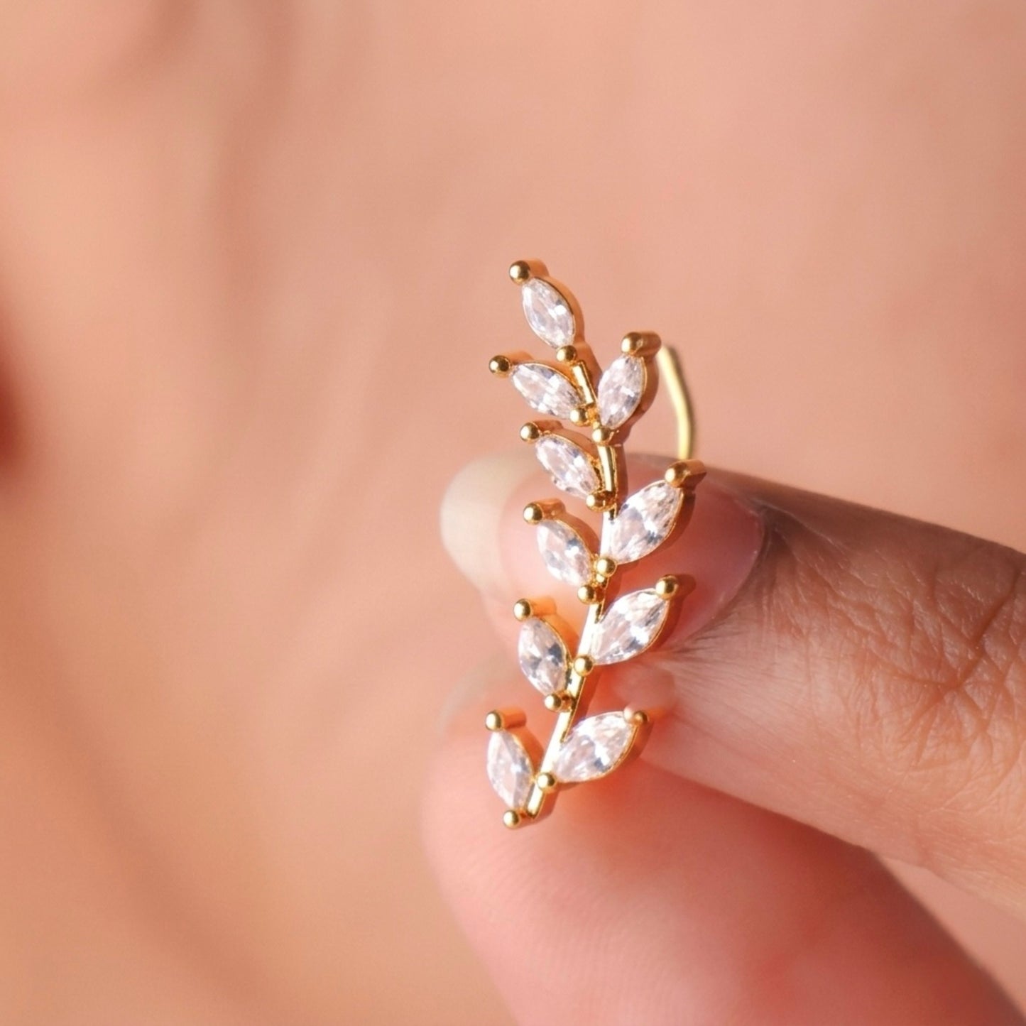 A close-view of a gold-plated laurel vine ear climber earrings for women featuring sparkling marquise-cut white leaves