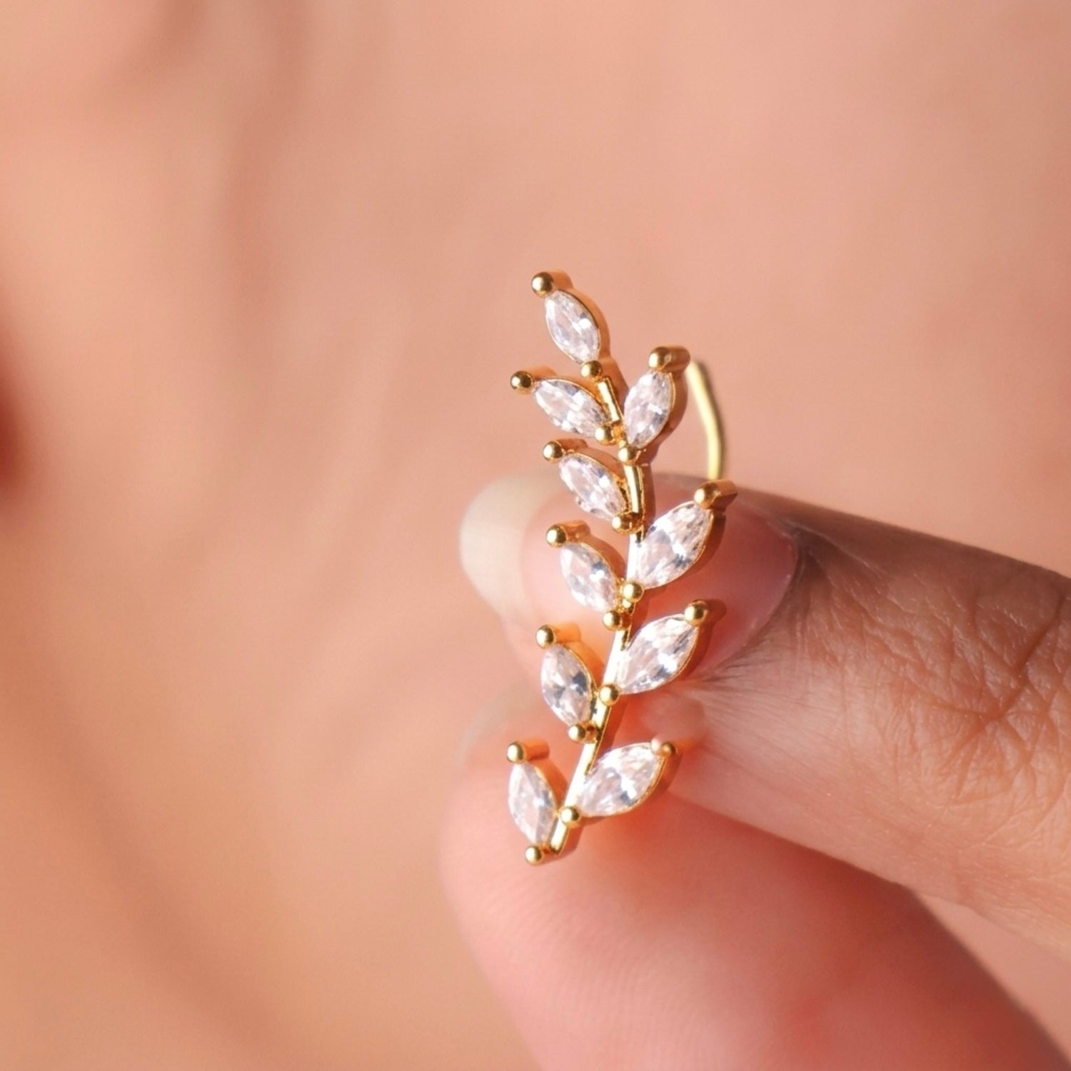 A close-view of a gold-plated laurel vine ear climber earrings for women featuring sparkling marquise-cut white leaves