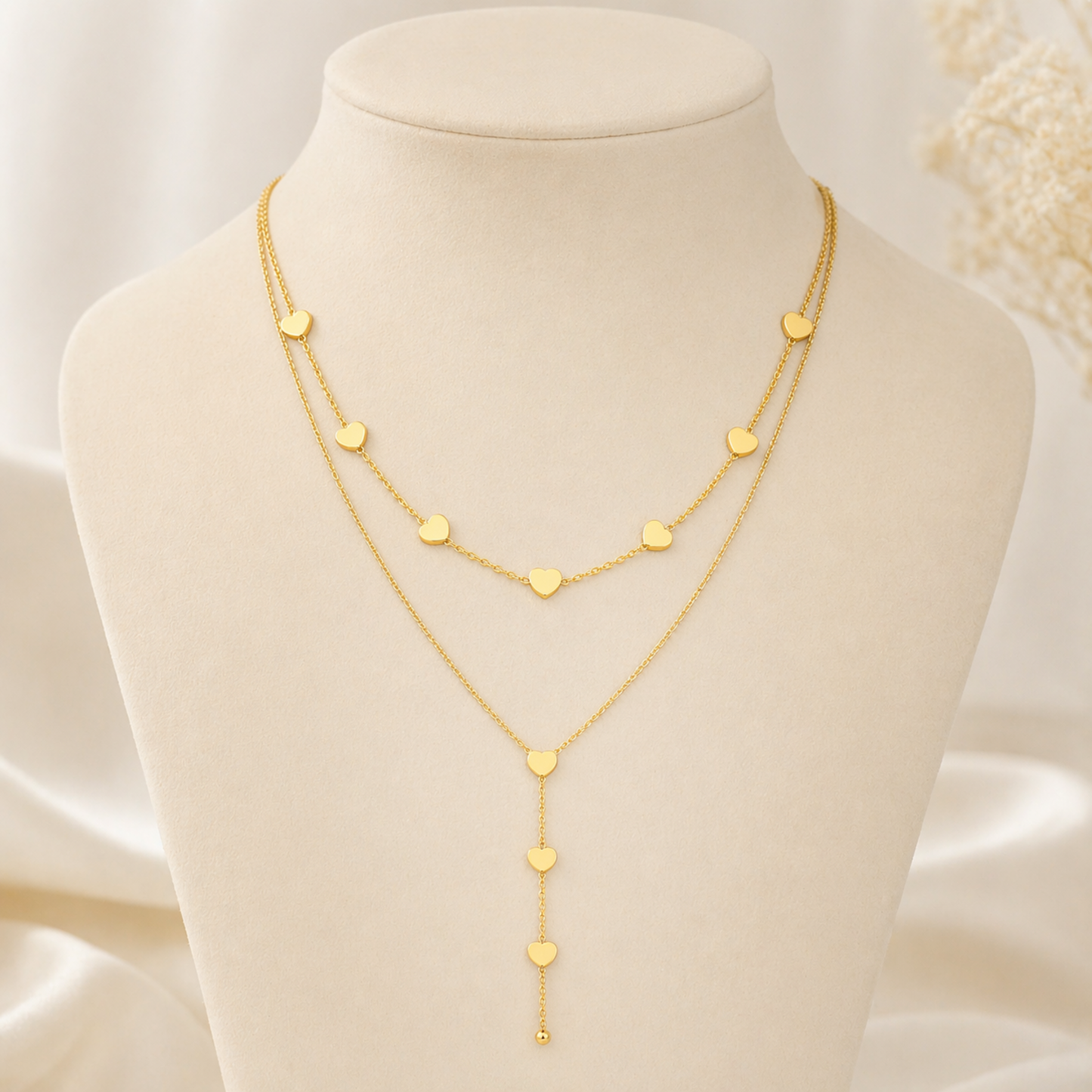 A close-view of a gold-plated stainless steel chain for women featuring a layered necklace design with multiple small heart charms and a long Y-shaped drop.