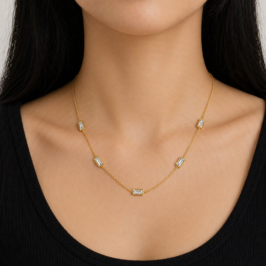A gold-plated stainless steel chain for women featuring five bezel-set baguette-cut crystal stations, shown on a model