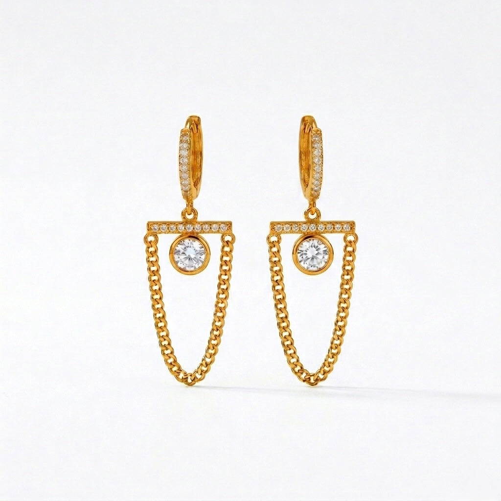 A pair of gold-plated long earrings for women featuring a hoop, a horizontal crystal bar, and a dangling gold curb chain loop, shown on a white background.