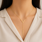 A gold-plated stainless steel chain for women featuring a minimalist V-chevron and a long vertical bar pendant, shown on a model