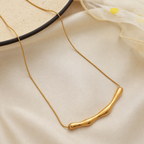 A gold-plated stainless steel chain for women featuring a horizontal, fluid-shaped "liquid gold" ripple bar pendant on a sleek snake chain
