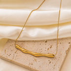 A gold-plated stainless steel chain for women featuring a horizontal, fluid-shaped "liquid gold" ripple bar pendant on a sleek snake chain