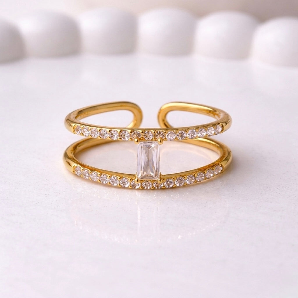 A modern gold plated adjustable ring for women with a double-band design on a white surface