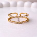 A modern gold plated adjustable ring for women with a double-band design on a white surface