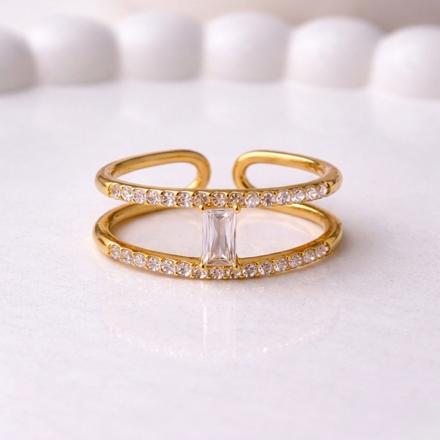 A modern gold plated adjustable ring for women with a double-band design on a white surface