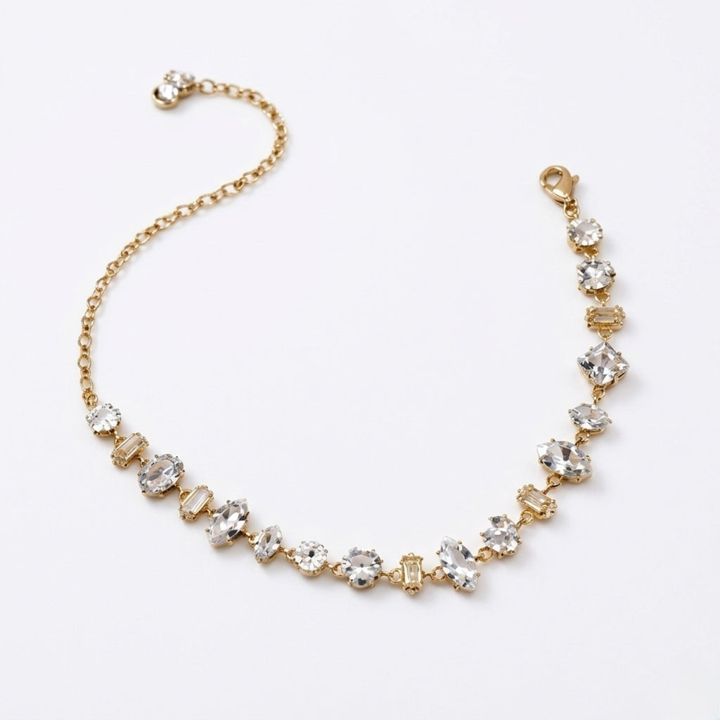 A gold-plated chain bracelet for women featuring an intricate mix of clear multi-shape stones, including brilliant, emerald, oval, and princess cuts, on a clean white background