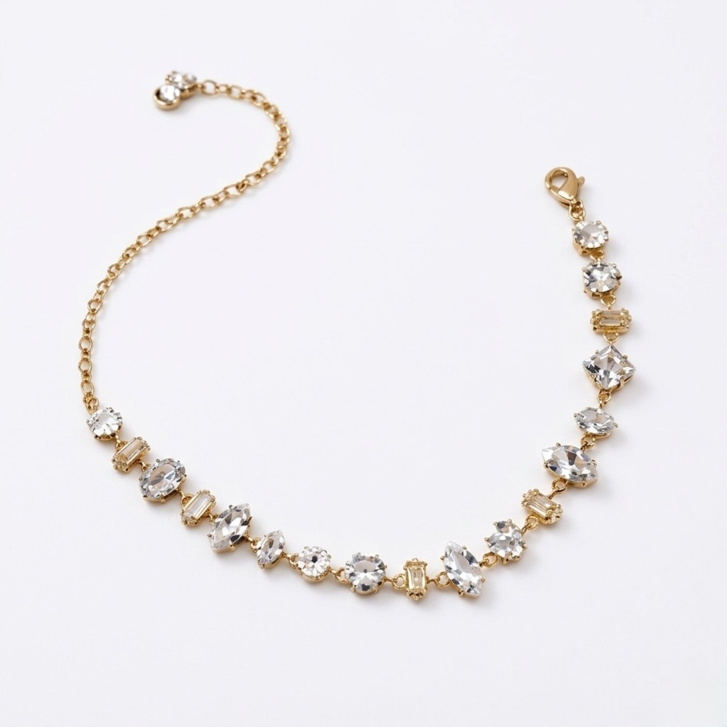 A gold-plated chain bracelet for women featuring an intricate mix of clear multi-shape stones, including brilliant, emerald, oval, and princess cuts, on a clean white background