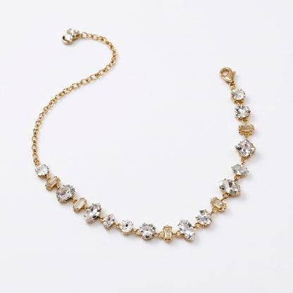 A gold-plated chain bracelet for women featuring an intricate mix of clear multi-shape stones, including brilliant, emerald, oval, and princess cuts, on a clean white background
