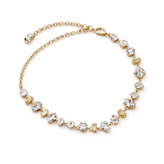 A  close-view of a gold-plated chain bracelet for women featuring an intricate mix of clear multi-shape stones, including brilliant, emerald, oval, and princess cuts, on a clean white background