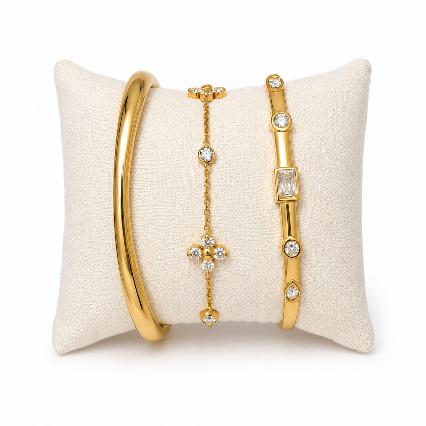 A premium three-piece gold-plated bracelet stack for women featuring a thick polished dome bangle, a delicate crystal flower charm chain, and a sleek baguette station bangle