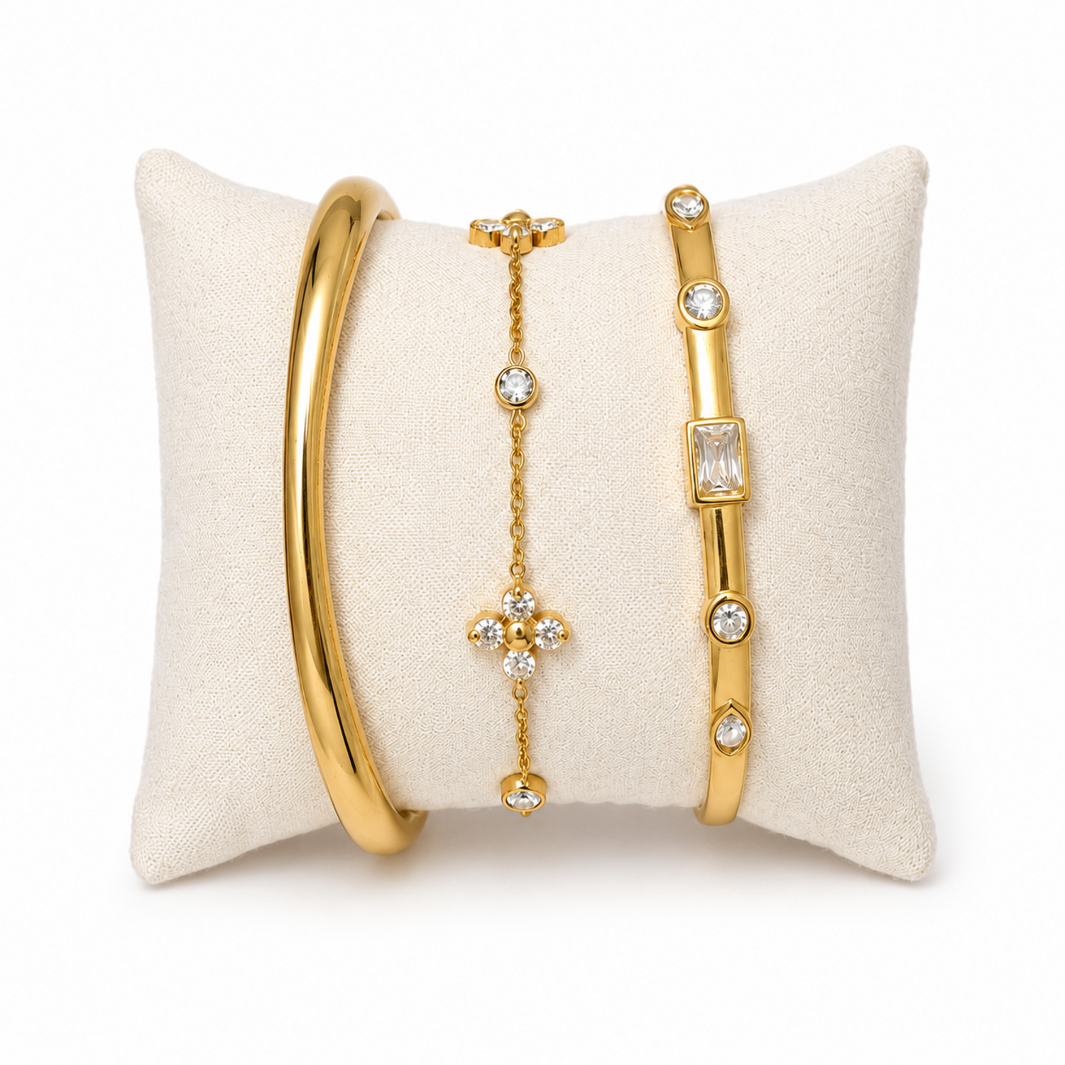 A premium three-piece gold-plated bracelet stack for women featuring a thick polished dome bangle, a delicate crystal flower charm chain, and a sleek baguette station bangle