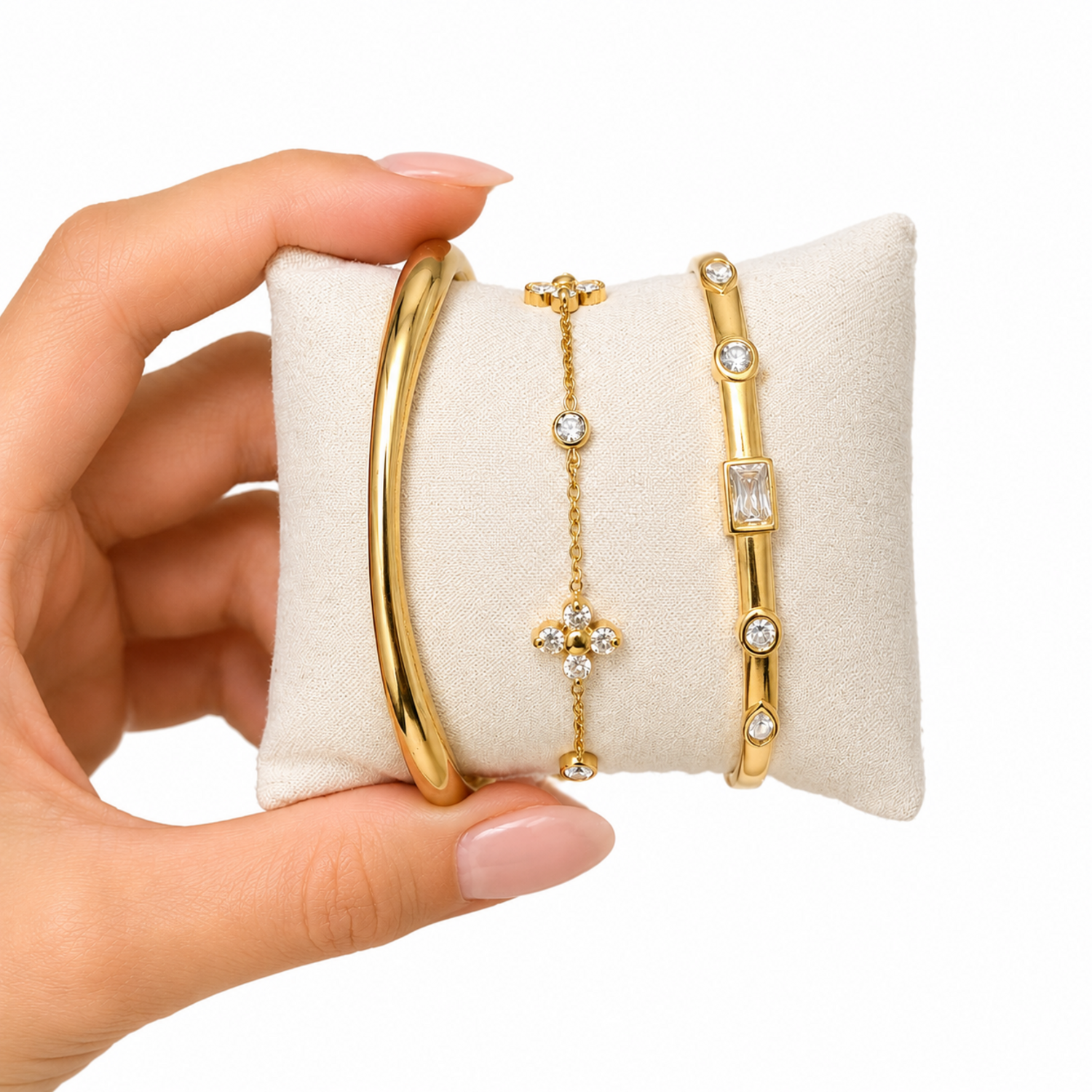 A close-view of a premium three-piece gold-plated bracelet stack for women featuring a thick polished dome bangle, a delicate crystal flower charm chain, and a sleek baguette station bangle
