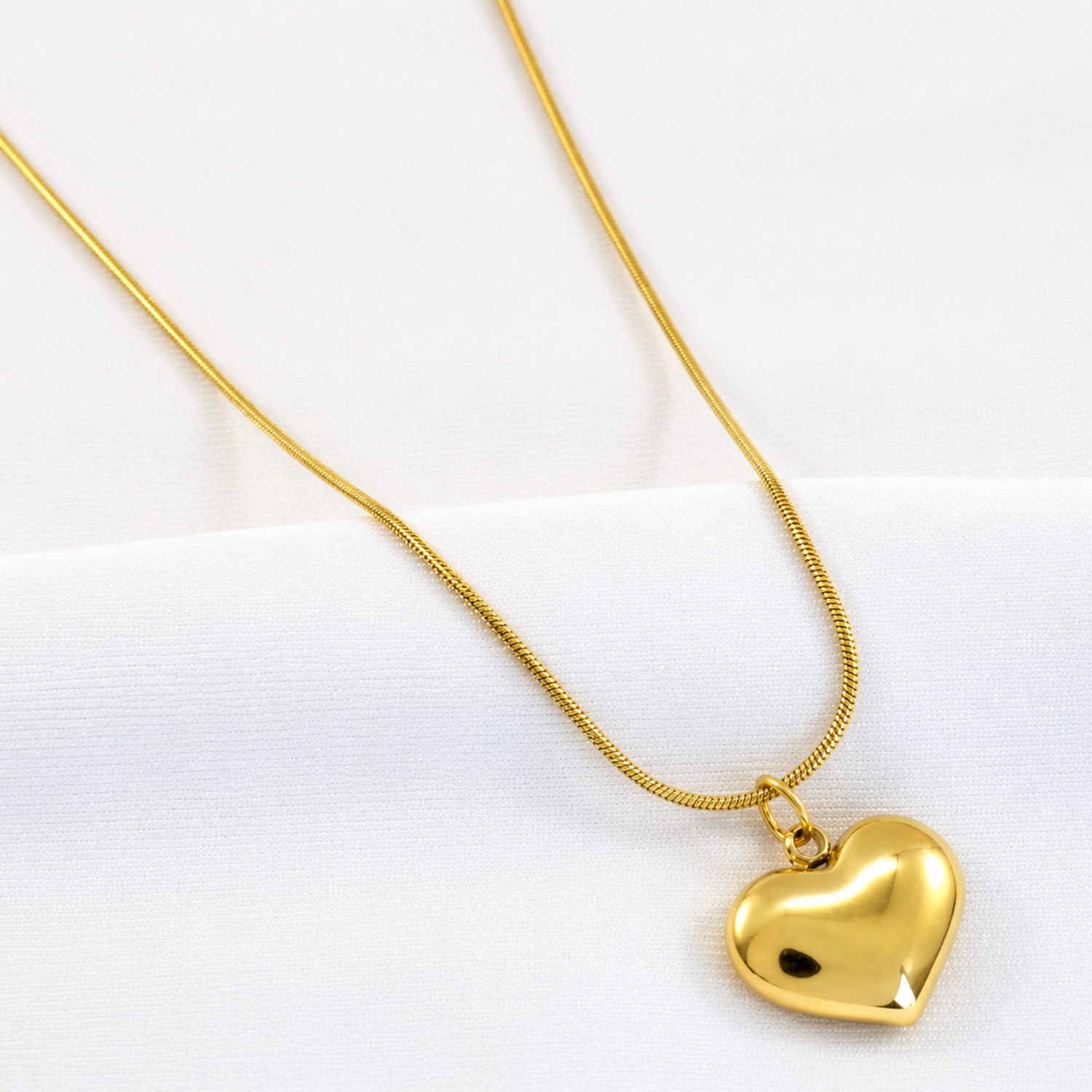 A close-view of a gold-plated stainless steel chain for women featuring a small, polished 3D puffed heart pendant on a delicate link chain