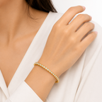 A gold-plated eternity bracelet for women featuring a continuous row of bezel-set round crystals and a secure side-clasp, shown on a model