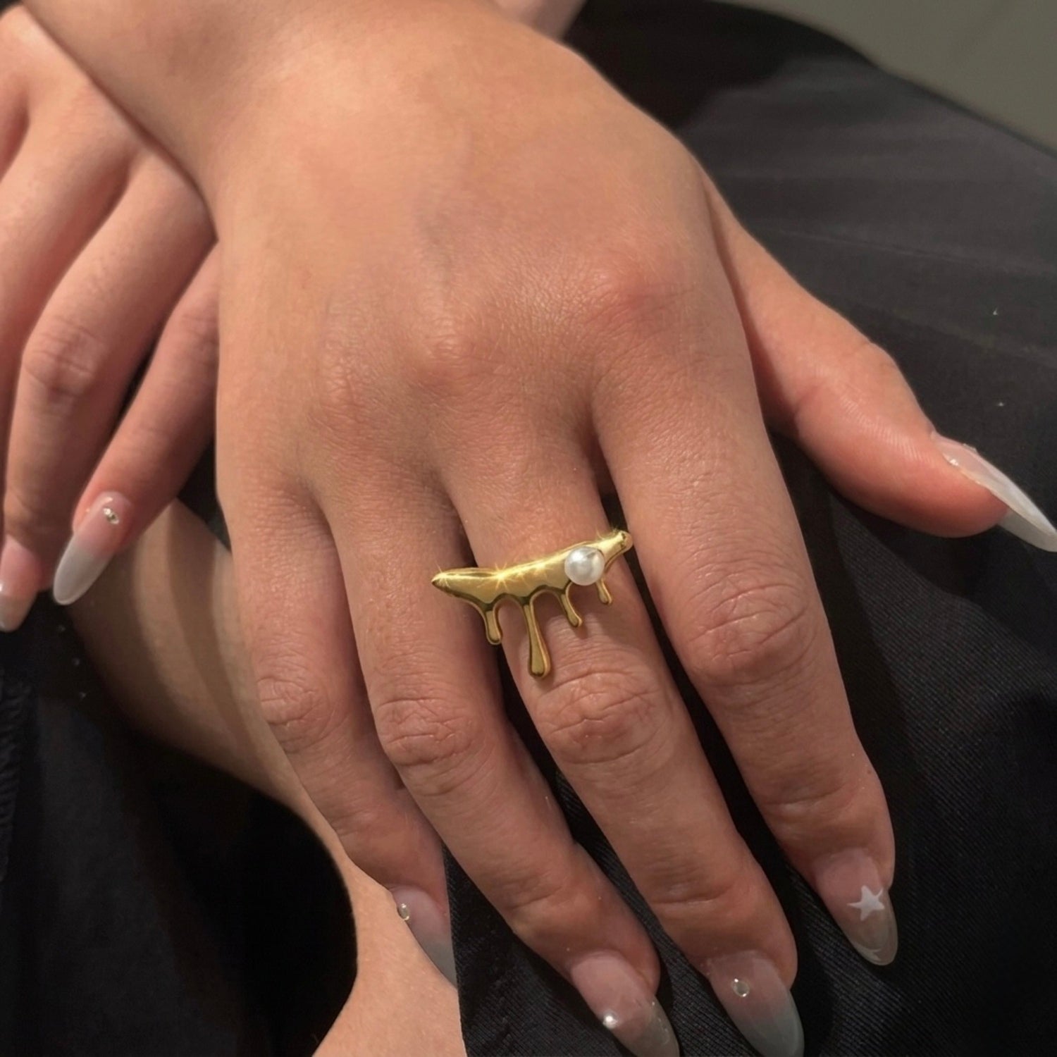 A unique 18kt gold plated stainless steel adjustable ring for women featuring a molten gold drip design with a single white pearl displayed on a model hand