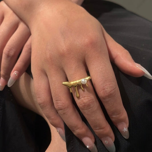 A unique 18kt gold plated stainless steel adjustable ring for women featuring a molten gold drip design with a single white pearl displayed on a model hand