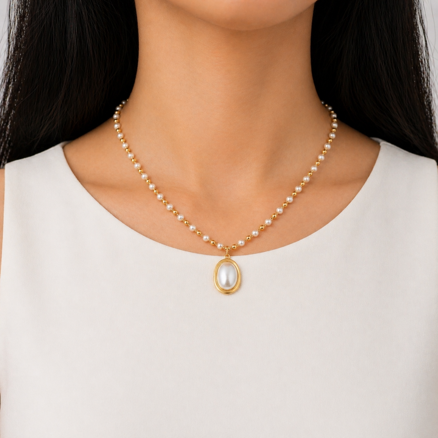A gold-plated stainless steel chain for women featuring alternating pearls and gold beads with a large oval pearl pendant, shown on a model