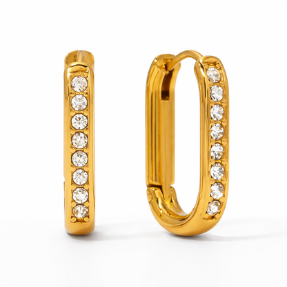 A pair of gold-plated rectangular hoop earrings for women featuring a vertical row of clear crystals, shown on a white background