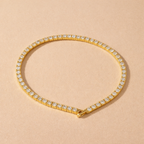 A gold-plated adjustable tennis bracelet for women on a cream background