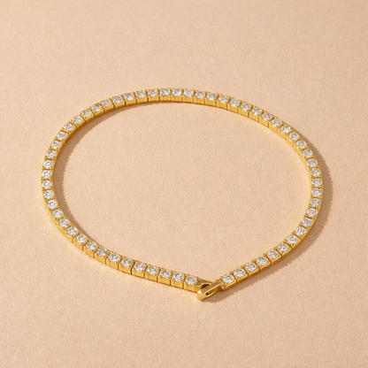 A gold-plated adjustable tennis bracelet for women on a cream background