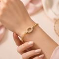 A close-view of a gold-plated chain bracelet for women featuring a large central oval link encrusted with crystals and round polished chain links