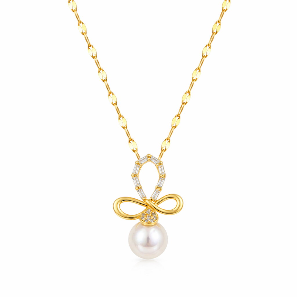 A gold-plated stainless steel chain for women featuring a crystal-encrusted bow pendant with a large white pearl drop, isolated on a white background