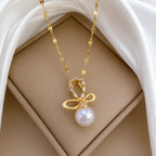 A close-view of a gold-plated stainless steel chain for women featuring a crystal-encrusted bow pendant with a large white pearl drop
