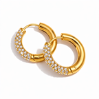 A pair of gold-plated thick hoop earrings for women featuring a front half encrusted with clear pavé crystals, shown on a white background.