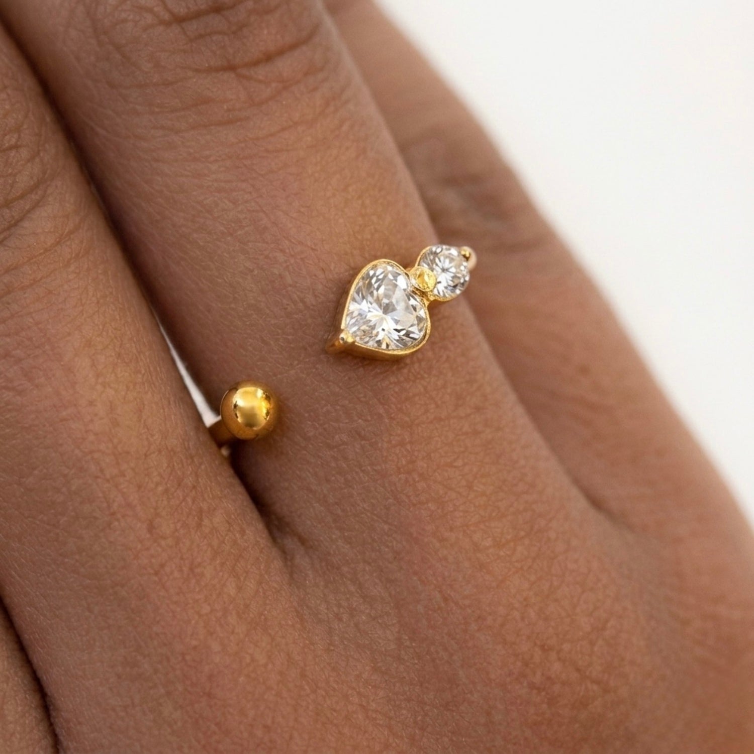 closeup view of a dainty 18kt gold plated stainless steel adjustable ring for women featuring three small clear white stones and a gold bead