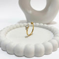 A dainty 18kt gold plated stainless steel adjustable ring for women featuring three small clear white stones and a gold bead on a white aesthetic jewelry tray