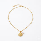 Gold bracelet with shell charm and pearl on a white background