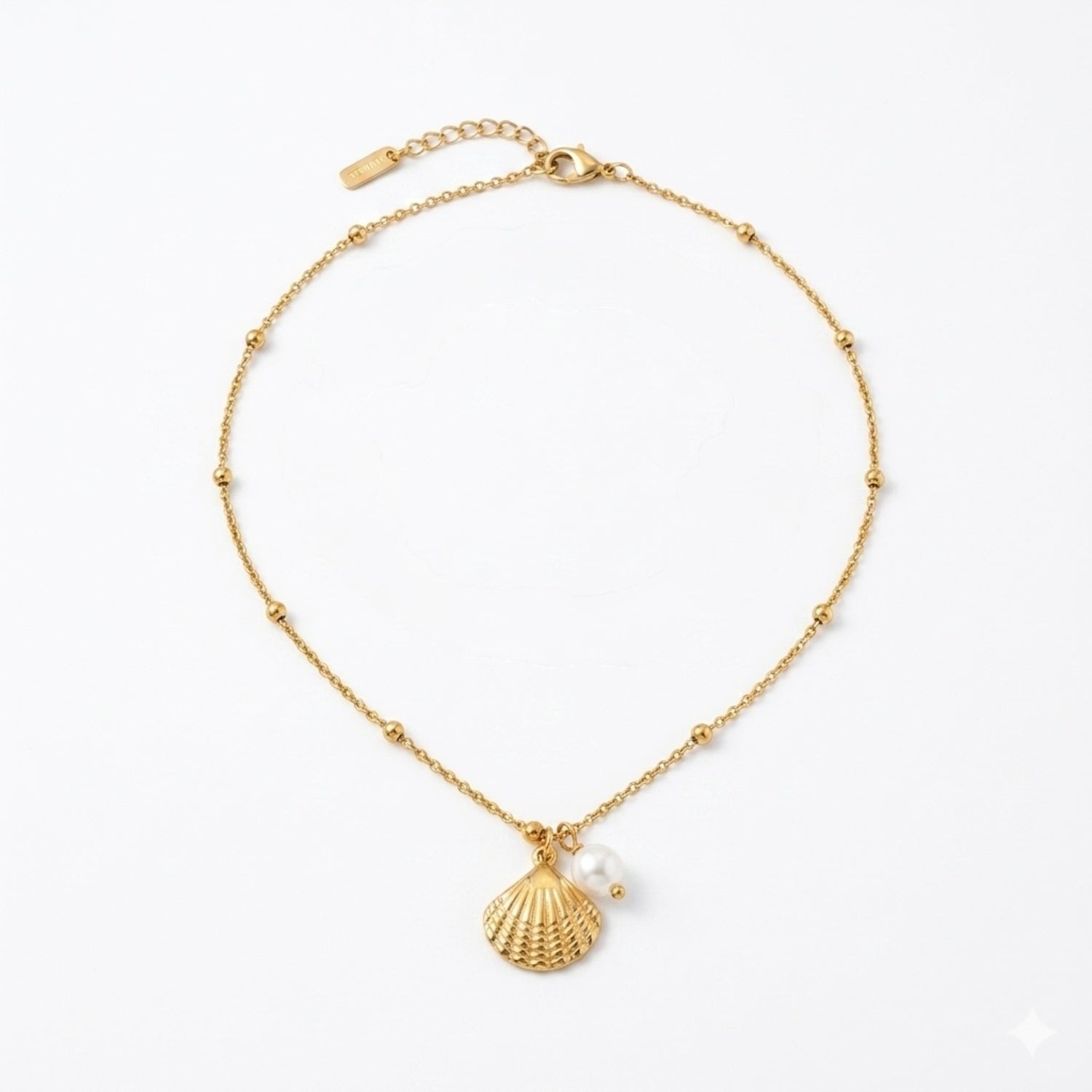 Gold bracelet with shell charm and pearl on a white background