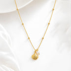 A gold-plated stainless steel chain for women featuring small bead stations and a shell pendant with a single pearl, set against a white background