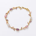 A gold-plated floral vine chain bracelet for women featuring lavender, pink, and clear oval and marquise-cut stones, shown on a clean white background