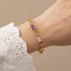 A gold-plated floral vine chain bracelet for women featuring lavender, pink, and clear oval and marquise-cut stones, shown on a model