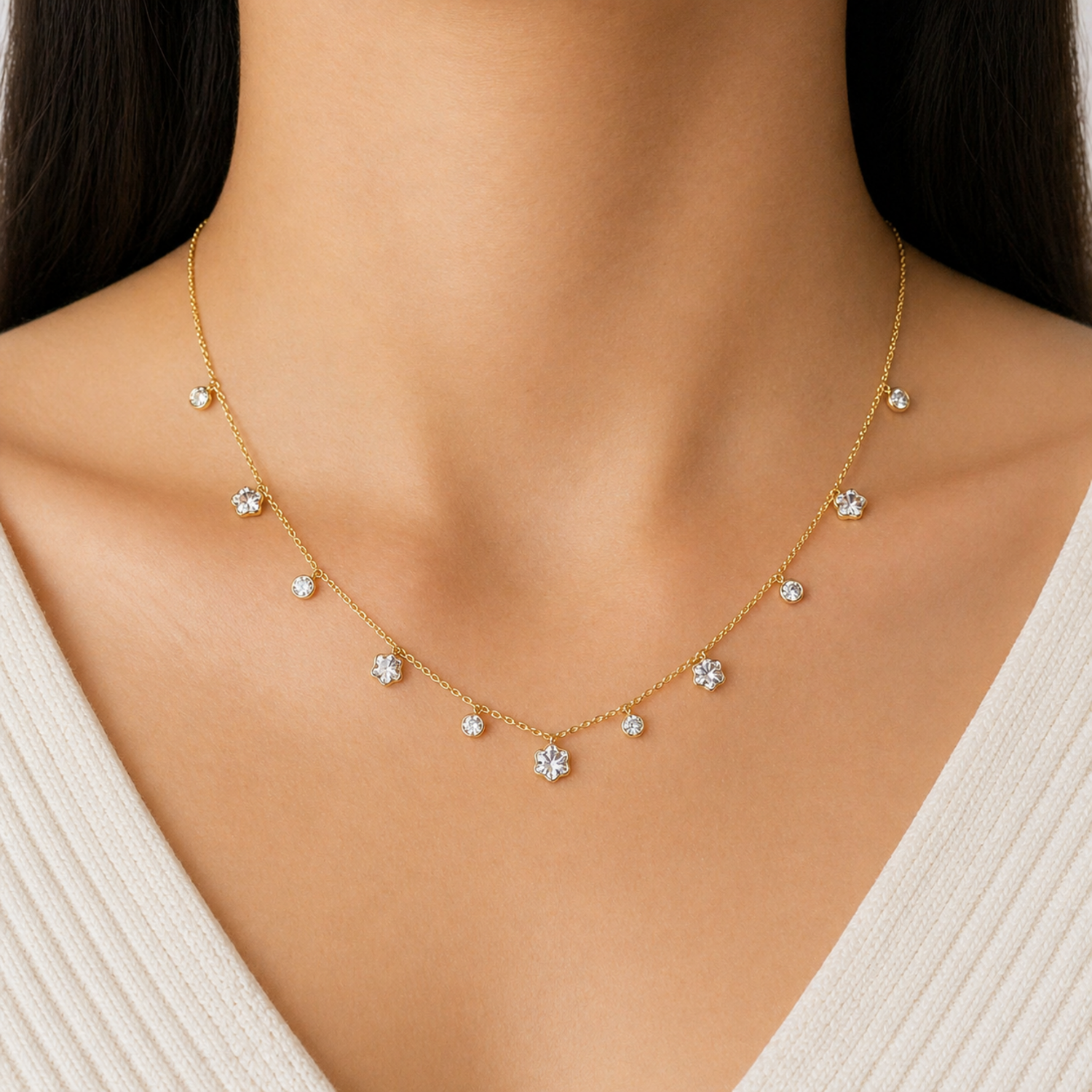 A gold-plated stainless steel chain for women featuring dangling crystal blossoms and round bezel-set crystal charms, shown on a model