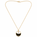 A gold-plated stainless steel chain for women featuring a circular pendant with black enamel wave patterns and a single floating crystal.