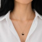 A gold-plated stainless steel chain for women featuring a circular pendant with black enamel wave patterns and a single floating crystal shown on a model