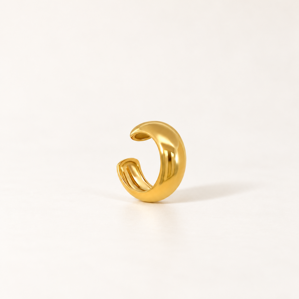 Gold-tone open ear cuff with a smooth rounded band and a row of clear crystals along the lower edge.
