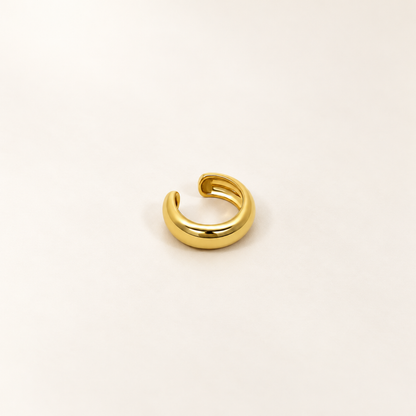A close-view of a Gold-tone open ear cuff with a smooth rounded band and a row of clear crystals along the lower edge.