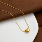A close-view of a gold-plated stainless steel chain for women featuring a tiny, puffed heart pendant on a delicate link chain