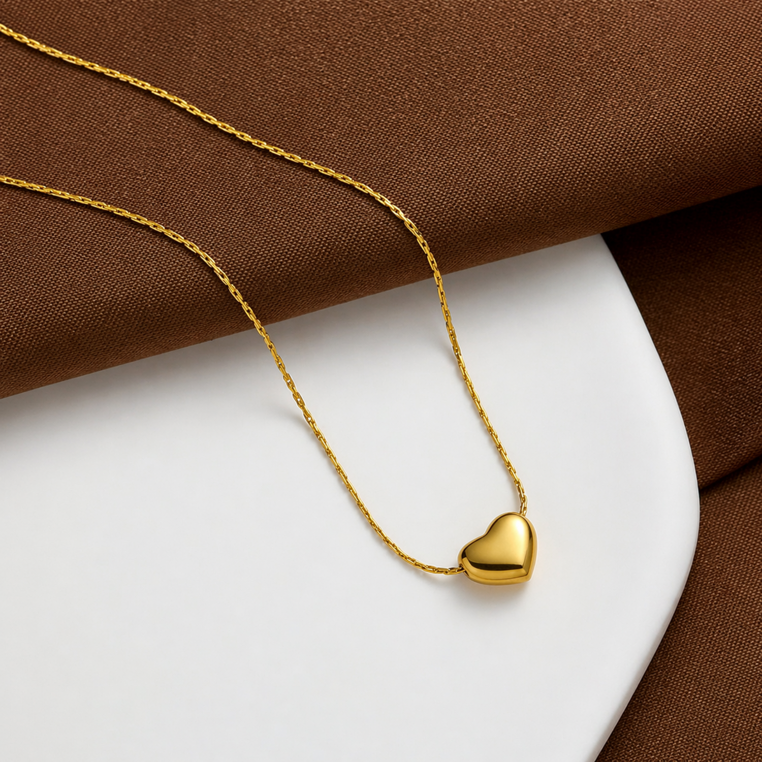 A close-view of a gold-plated stainless steel chain for women featuring a tiny, puffed heart pendant on a delicate link chain